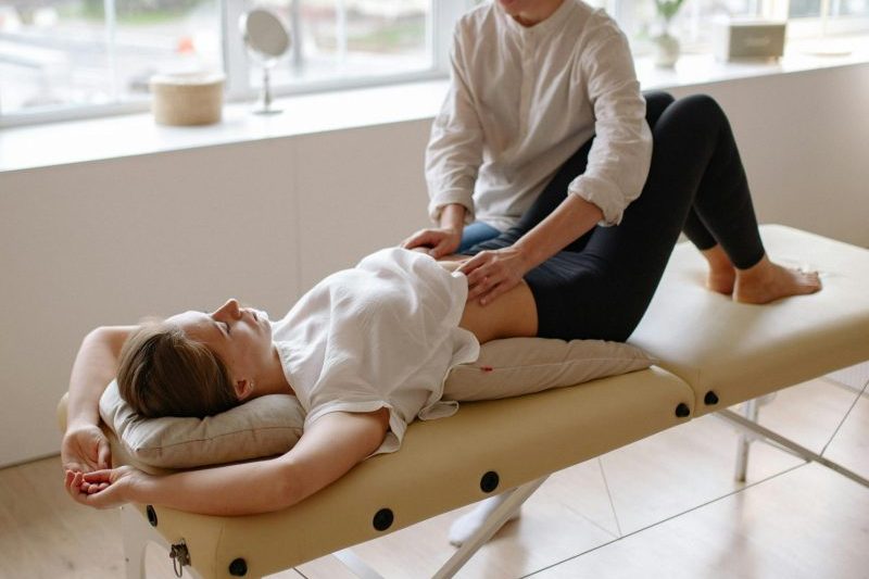 A massage therapist working on a client in a naturally lit room.